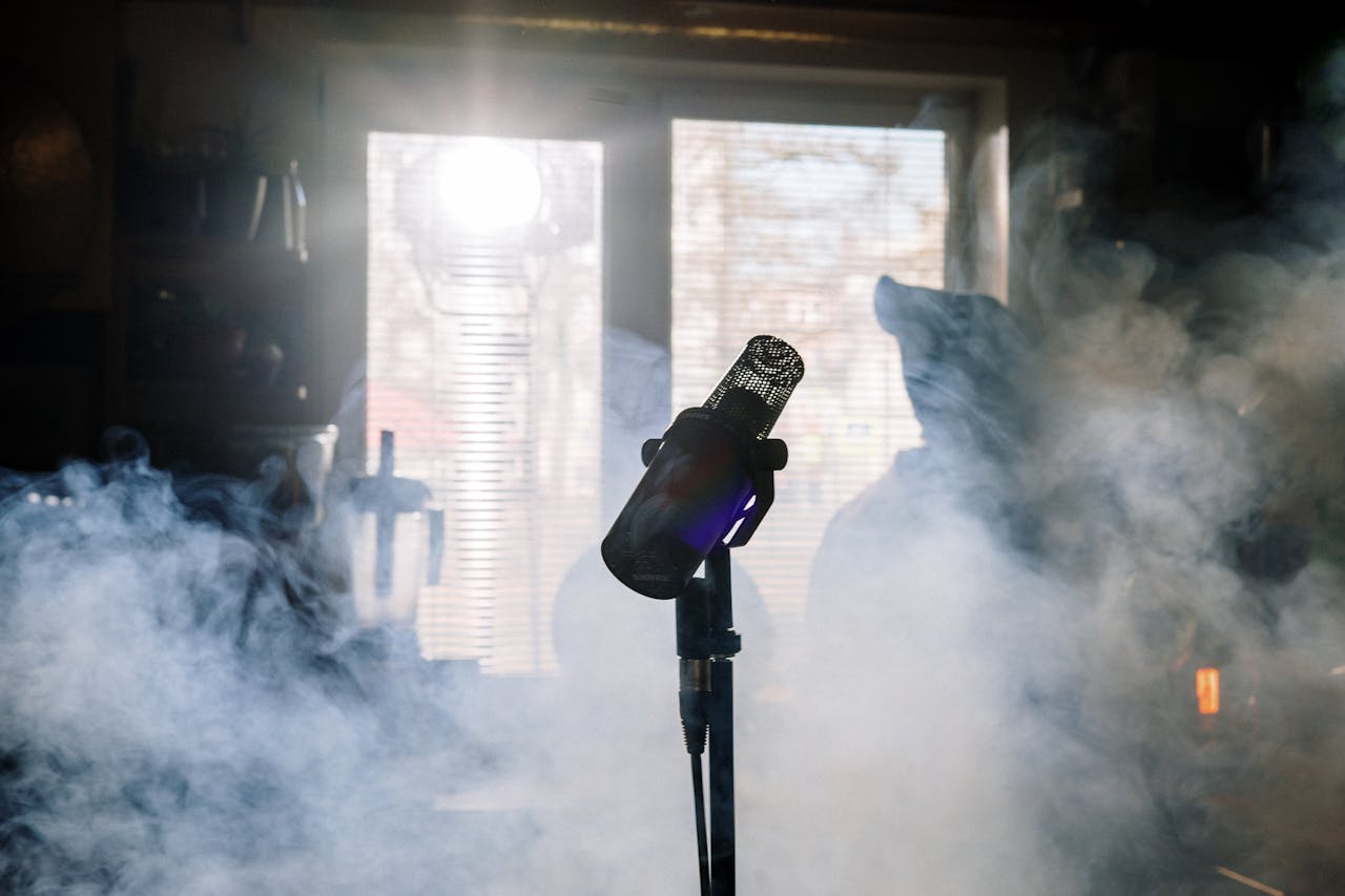 A moody home studio setup featuring a microphone amidst smoke and sunlight.